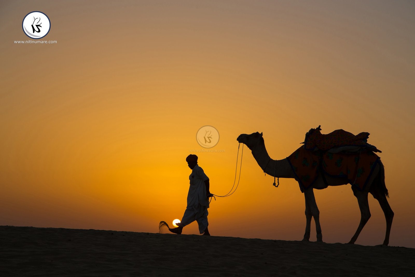 Nice landscape having golden color of sunrise captured with walking person and his camel.